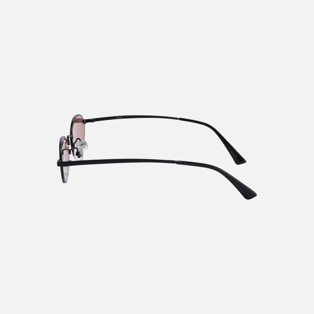 Miraje oval frame sunglasses featuring a slim black metal frame and warm amber-tinted lenses, side profile view.